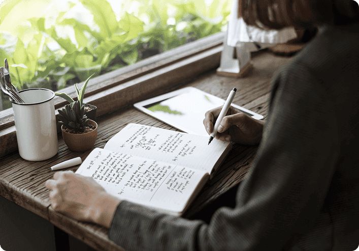 A writer working at a desk beside a window